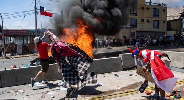 Demonstranten mit chilenischen Nationalfahnen verbrennen Zelte